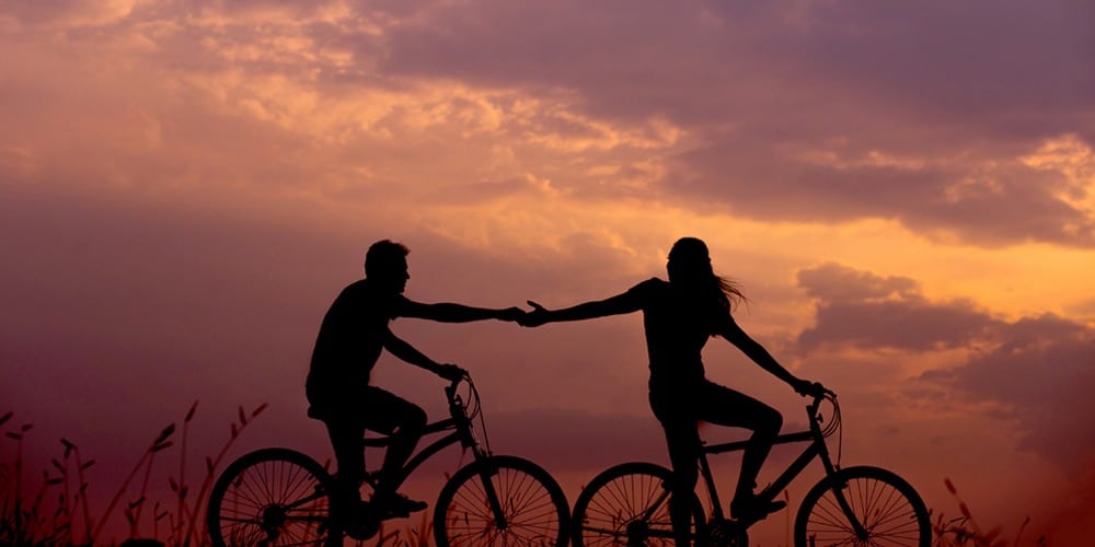 Bicycle riders holding hands